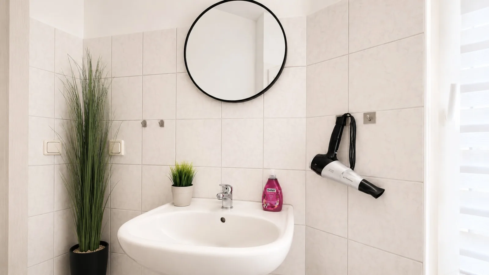 Waschbecken mit Rundspiegel und Föhn