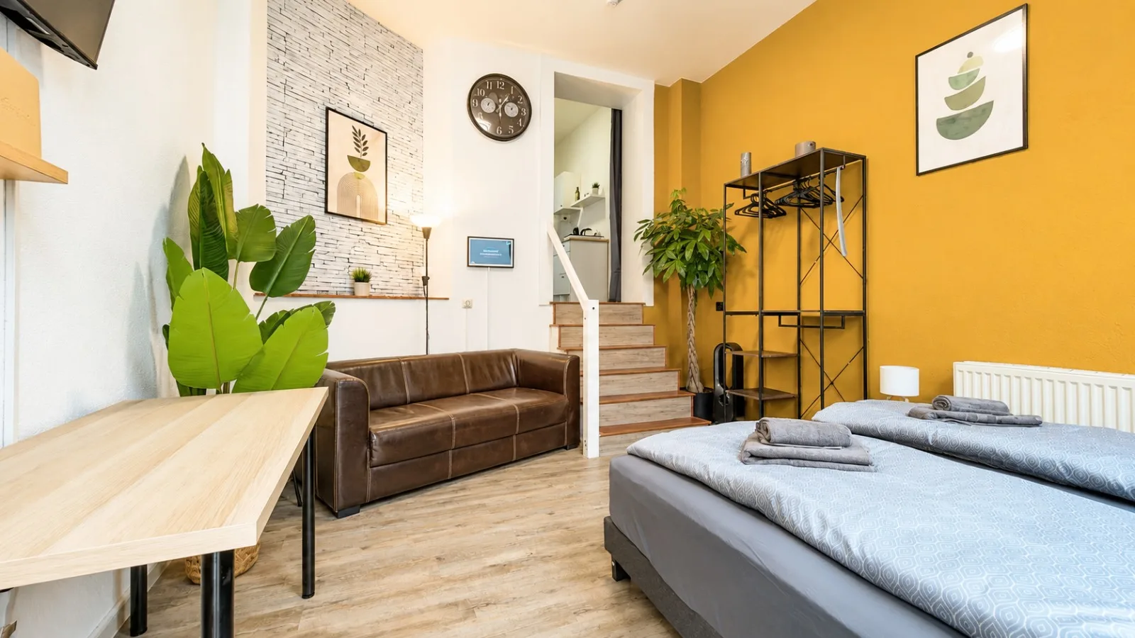 Wohn- und Schlafbereich mit Sofa, zwei Einzelbetten und senfgelber Wand