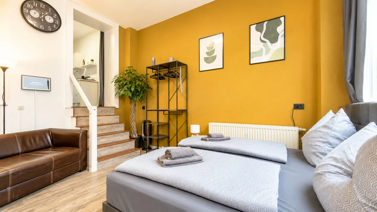 Schlafbereich mit Betten, Kleiderständer und Treppe zur Küche